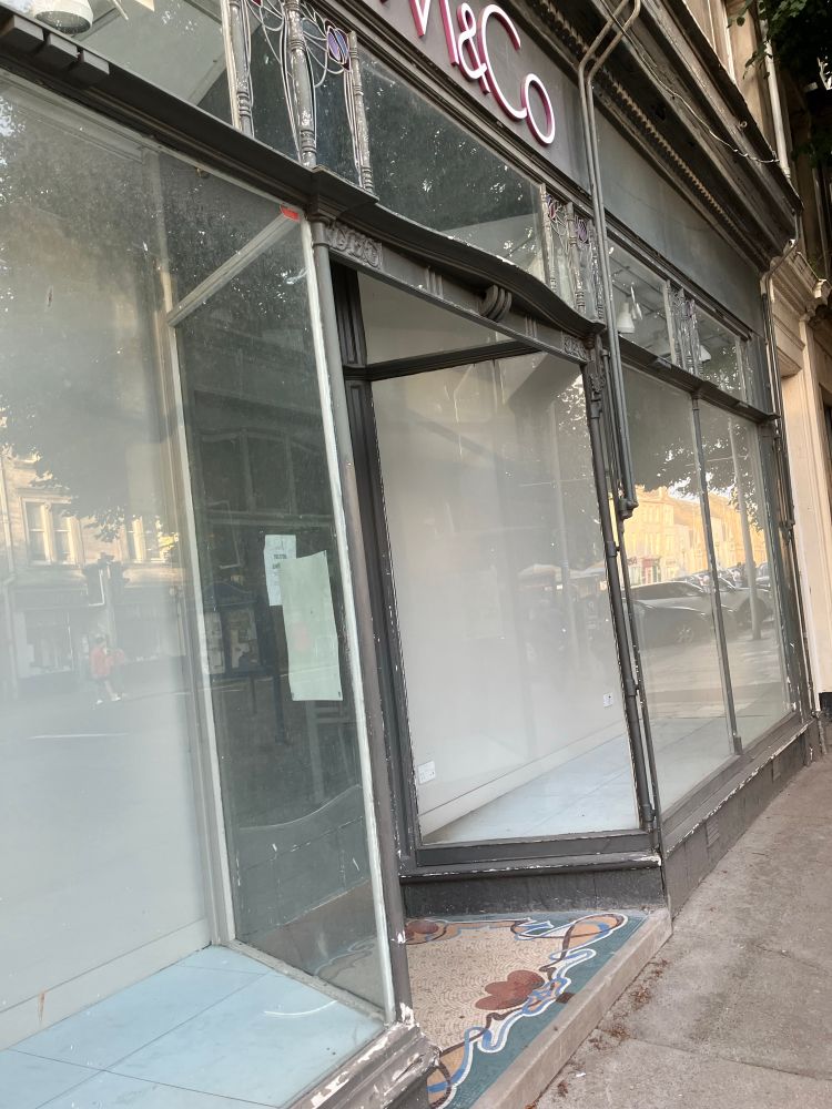 Grey timber shopfront with large panes of glass and recessed entrance.