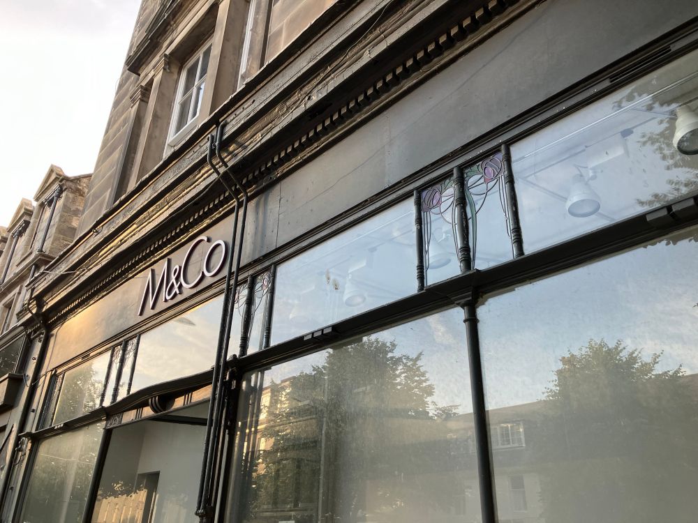 Timber shopfront with letters saying M&Co. Think glazing bars and stained glass 