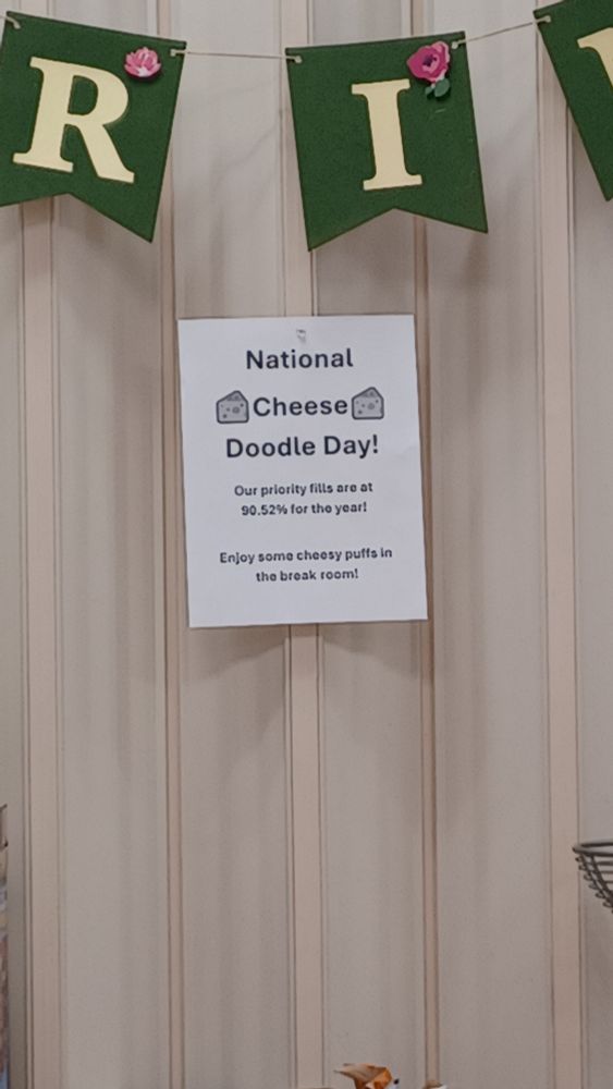 postet pinned to wall in breakroom. 
text reads, National Cheese Doodle Day our priority fills are at 90.52% for the year! Enjoy some cheesy puffs in the break room!
