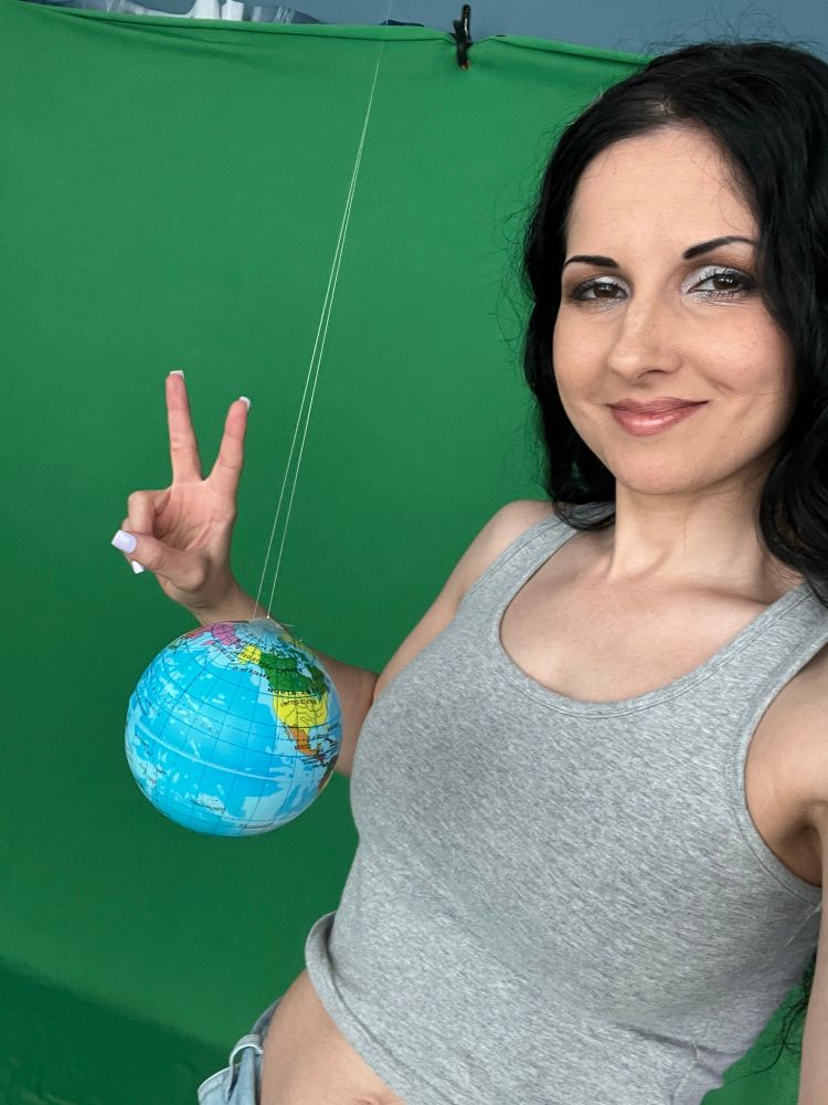 Hannah brunette fetish actress poses on green screen with tiny earth globe dangling in frame