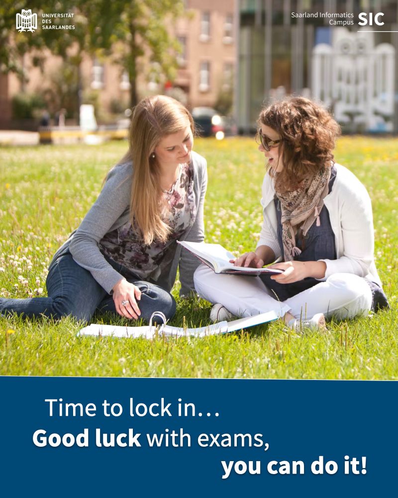Two women studying on the grass, near the campus center.