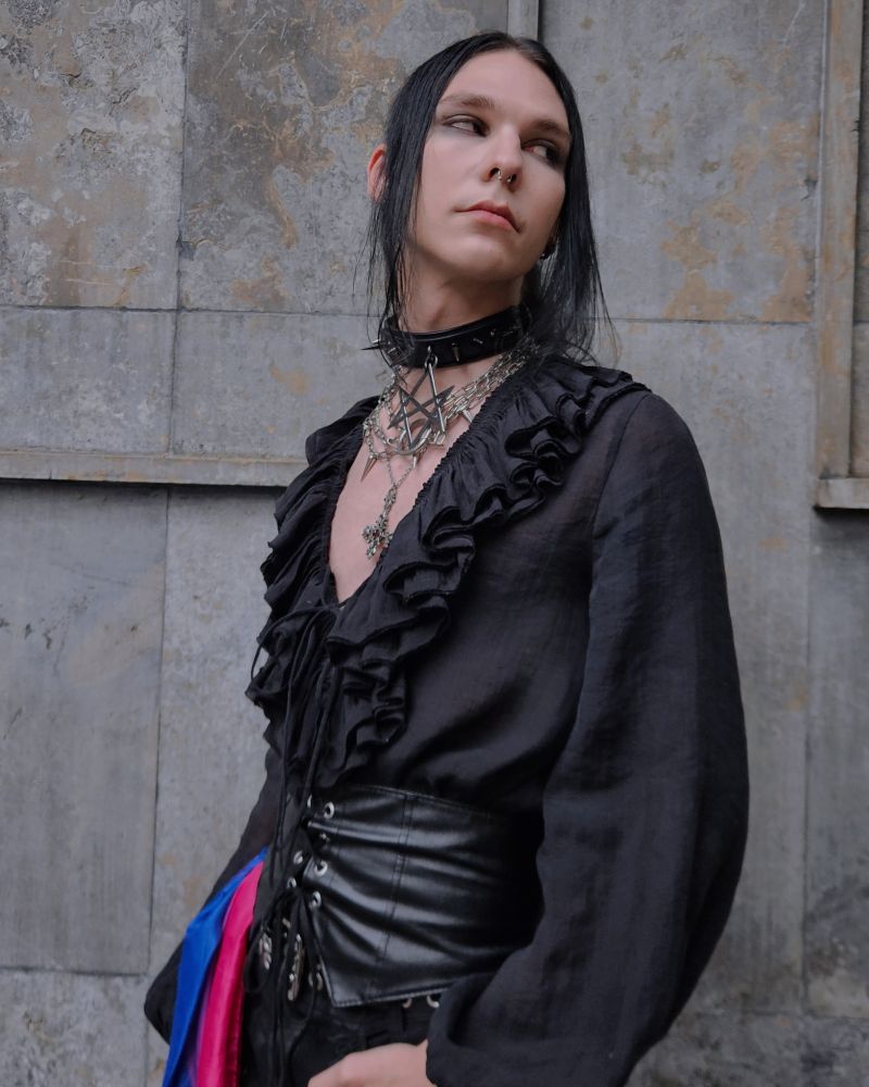 Picture of me with many chains, a black blouse and a leather corset. I have a Bi flag on my side 