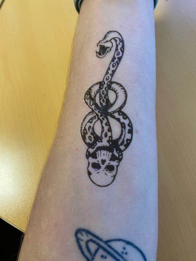 Photo de mon bras avec le fameux tatouage des Mangemorts de Harry Potter. C’est une sorte de tête de mort dont le corps est un serpent qui a l’air un peu malade.