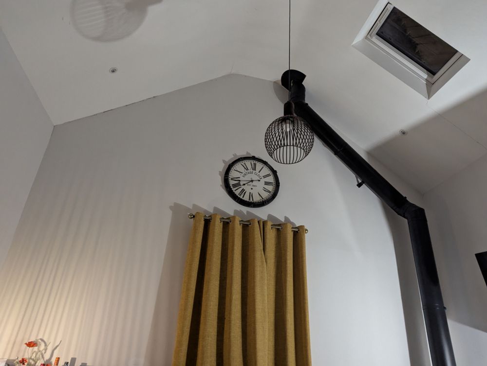 A high ceiling room with long curtains and an indoor chimney