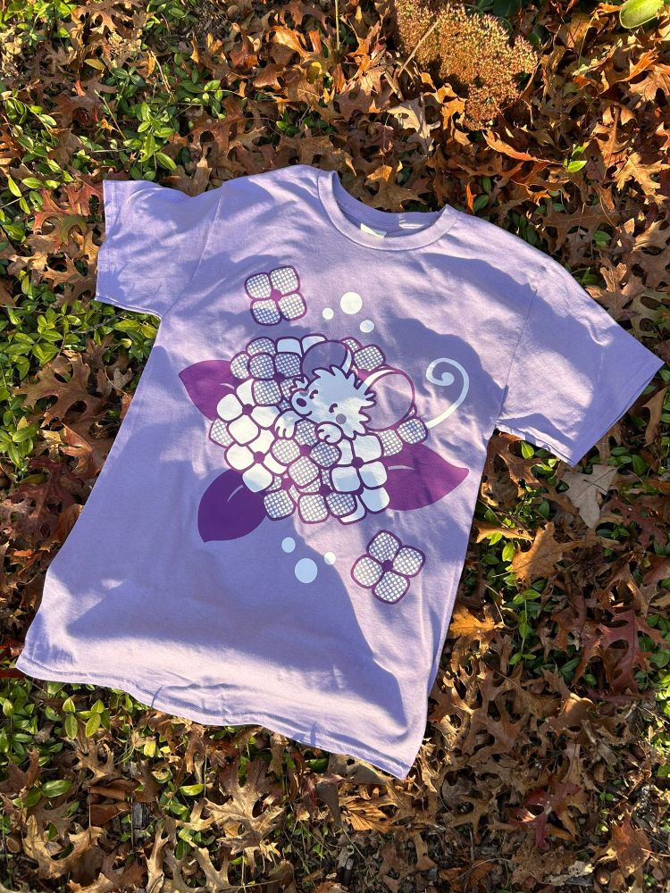 Photo of a light purple shirt with a darker purple and white design of a mouse popping out of some hydrangea flowers.