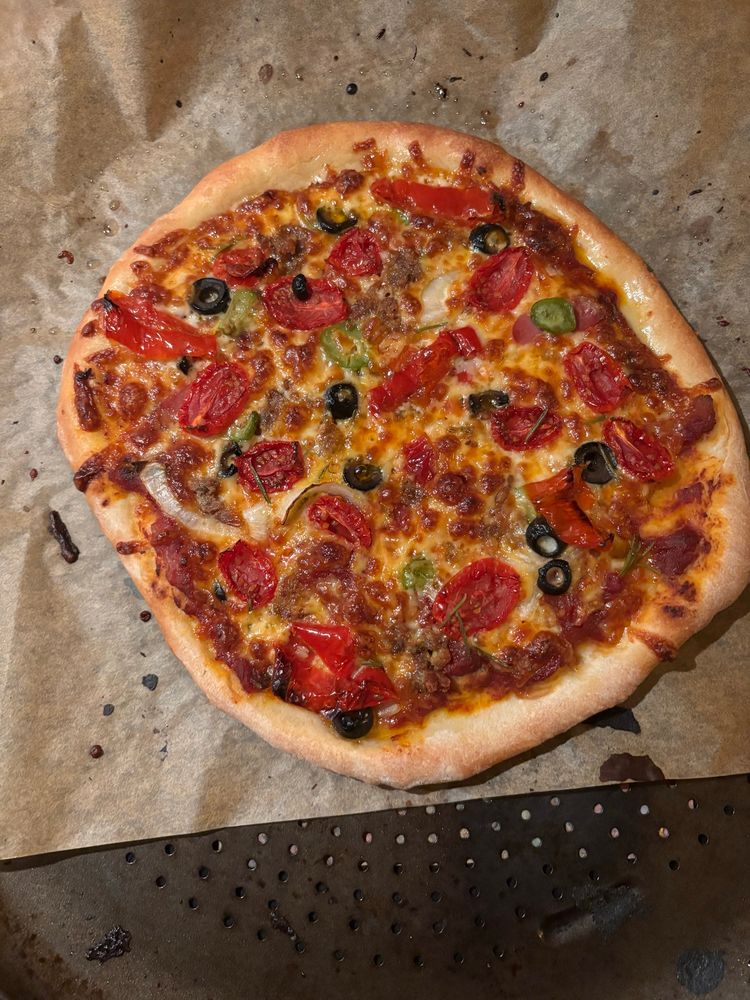Whack ass shaped pizza with black olives, tomatoes, green olives, onion and peppers, right out of the oven