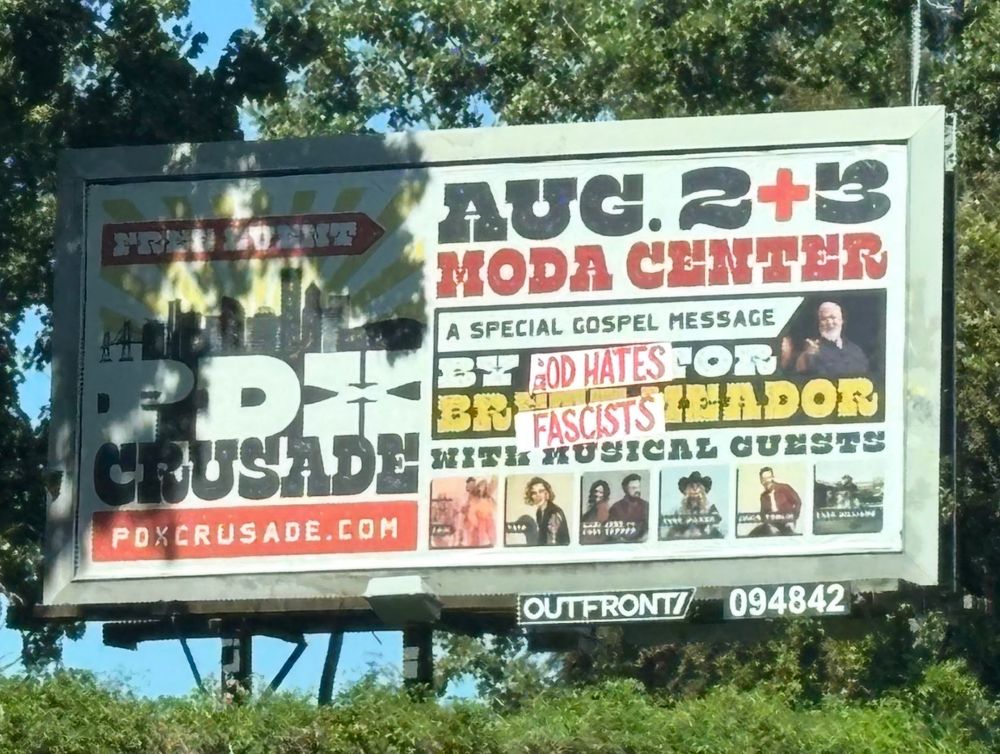  A photo of a billboard for an event called "PDX Crusade." The words "GOD HATES FASCISTS" has been affixed to the billboard.