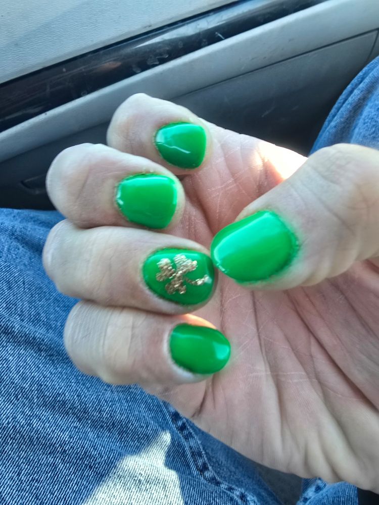 Green nails with a golden shamrock on the ring finger. 