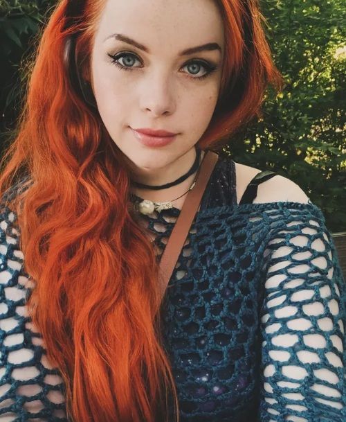 red haired girl with a mesh top sitting in a park
