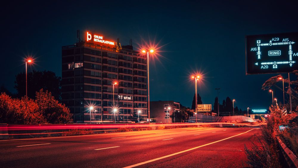 A nighttime view of a highway with an appartment complex in the background