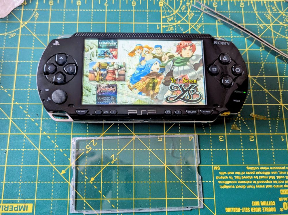 The glass lens has been installed and the PSP is on, showing the games menu