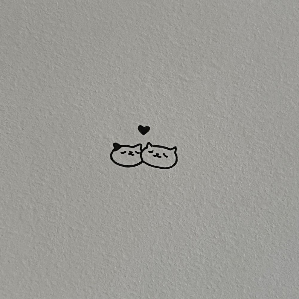 two cat heads snuggling with a heart above them