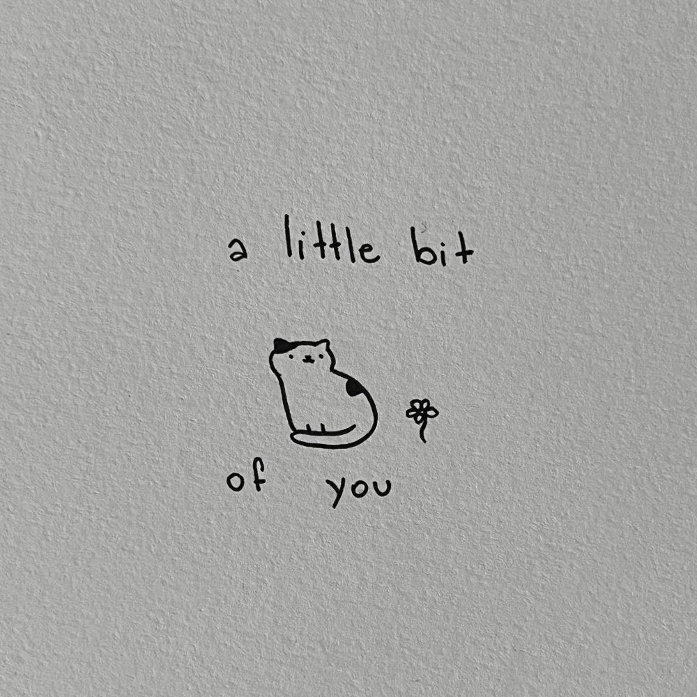 a sitting cat next to a small flower, with the text 