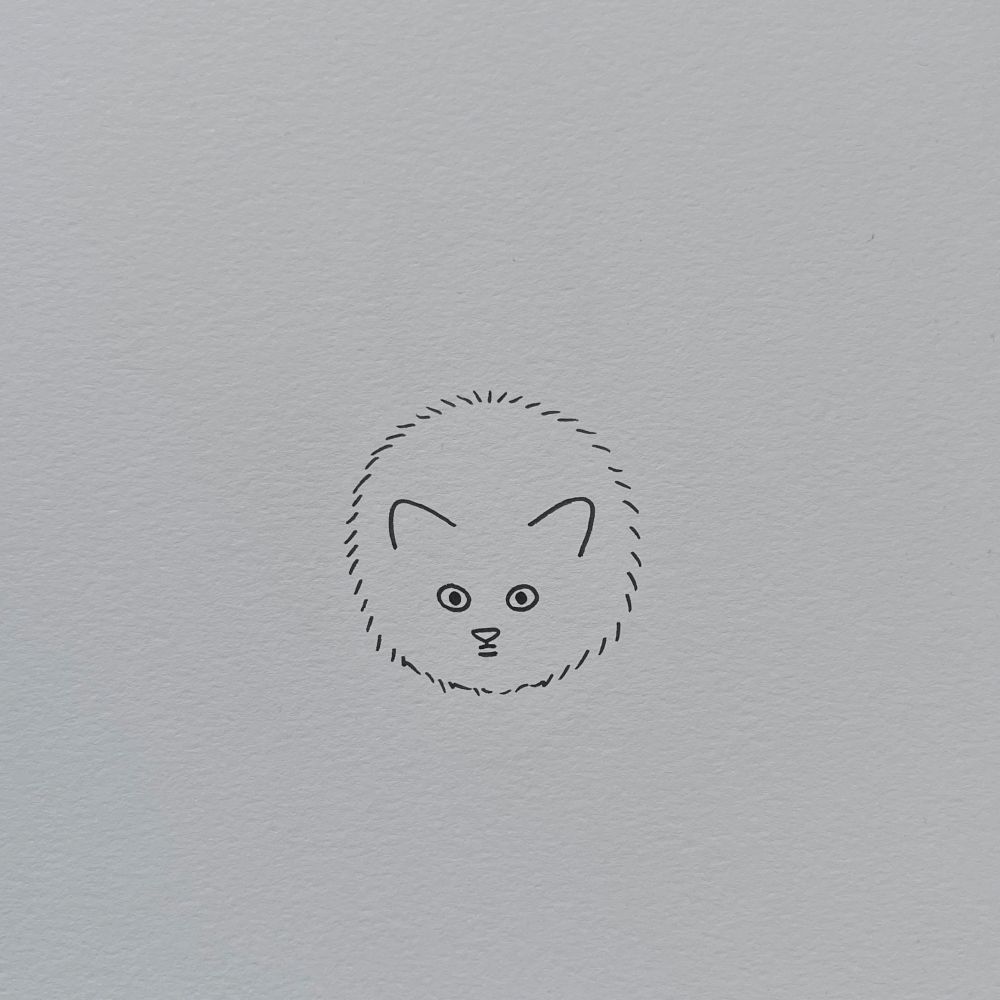 a poorly drawn cat, the outline is a soft oval shape with short strokes suggesting fur. inside it there are two ears, round eyes, and a small mouth and nose form a simple cat face (with a shape resembling a mold spore)