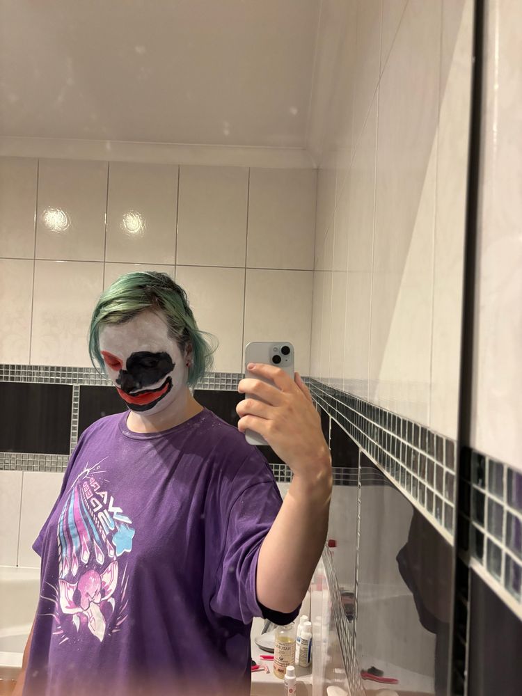Moi, dans la salle de bains, avec un maquillage de clown sombre mal fini car je débute. Tête baissée.