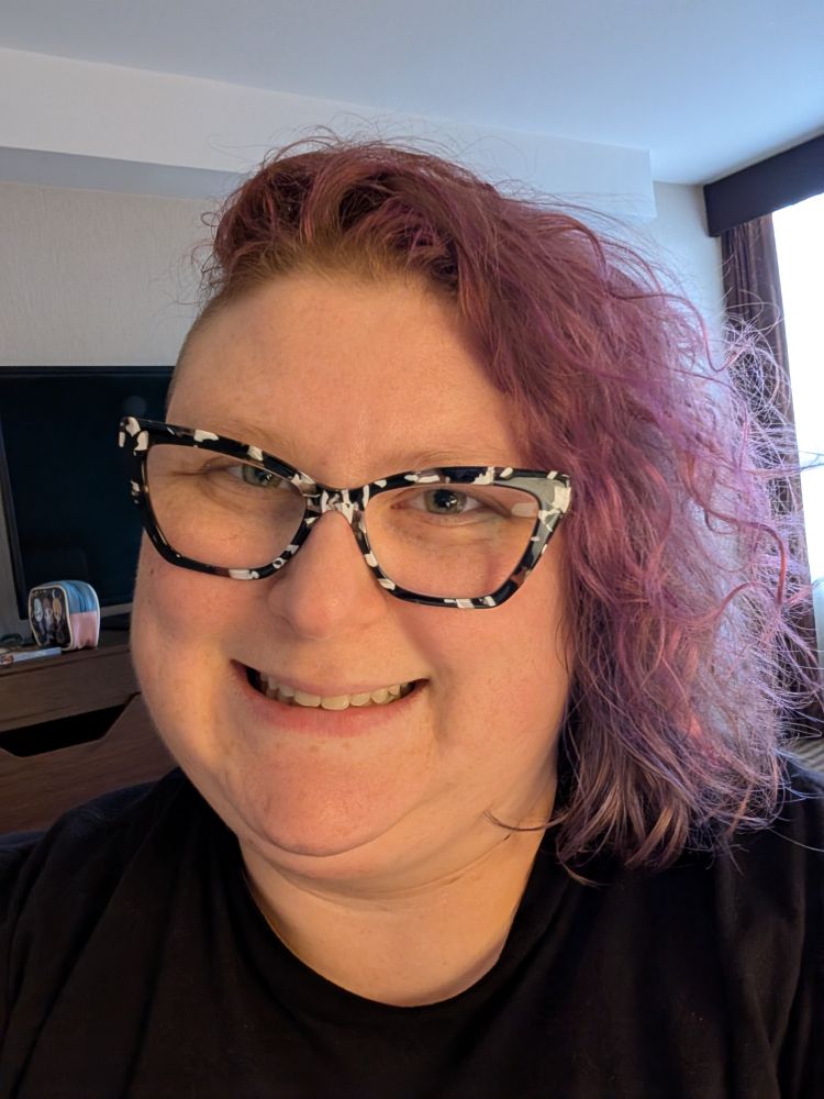 Photo captioned "12am June 1st" 
A selfie of the same smiling white woman from the first photo. But her curly hair is dyed shades of purple that range from magenta and orchid to plum and then a violet indigo that are styled to resemble an ombre.