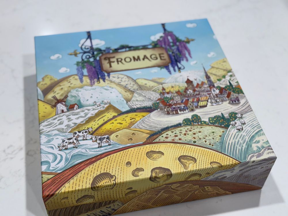 The box for the boardgame Fromage. It has a landscape made out of wheels of cheeses and a cute little village thing. 