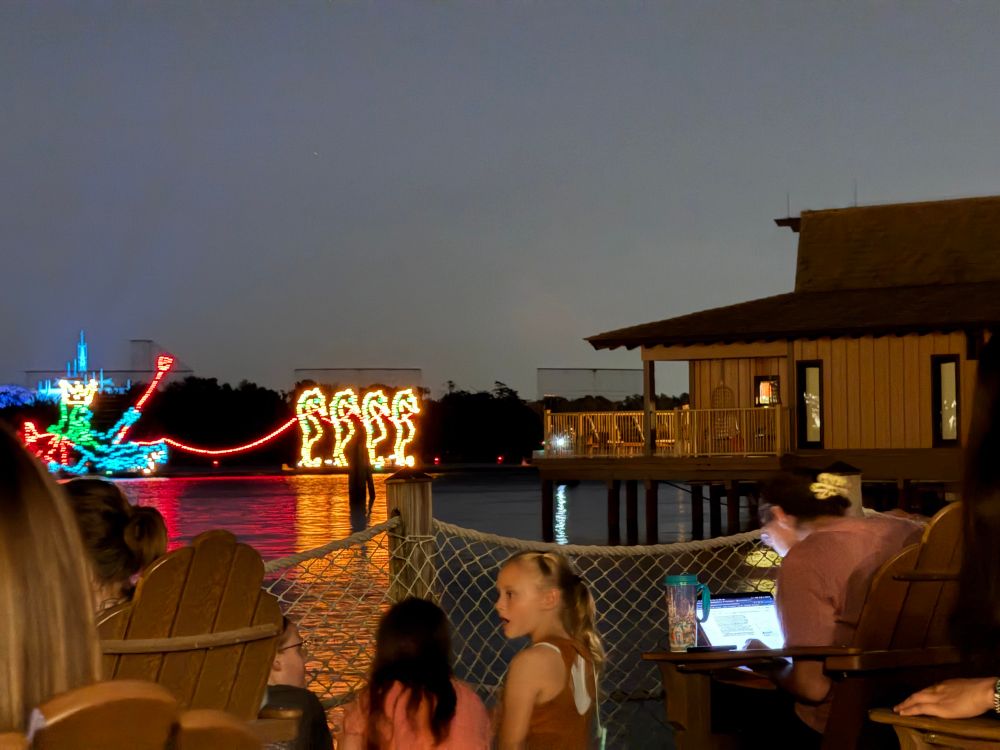 A woman working furiously on her laptop in a prime seat on the beach at the Polynesian Resort. The boats from Disney’s electric water pageant are in the background. 