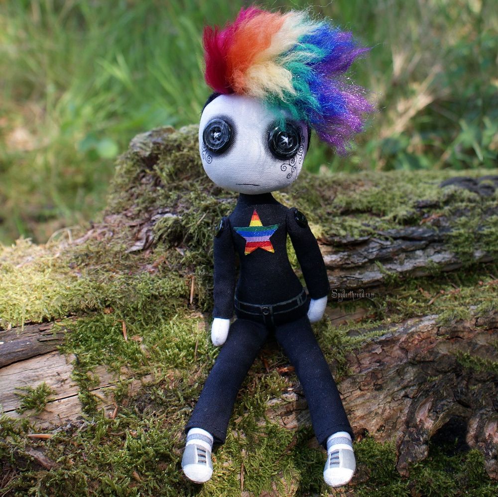 a button eyed art doll with punky rainbow hair in black skirt and pants with rainbow star on chest