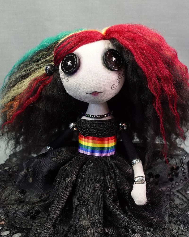 close up of a button eyed art doll in black lace dress with rainbow coloured hair and belt