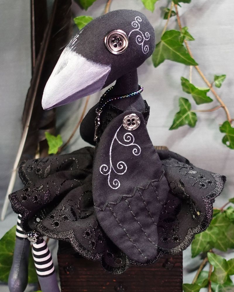 a black crow art doll with hand stitching and decorative line detail on wings