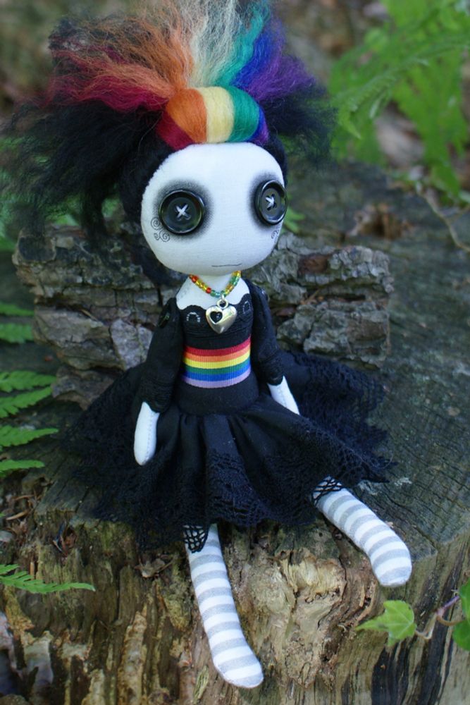 a button eyed doll in black dress with rainbow belt, necklace and stripes in hair