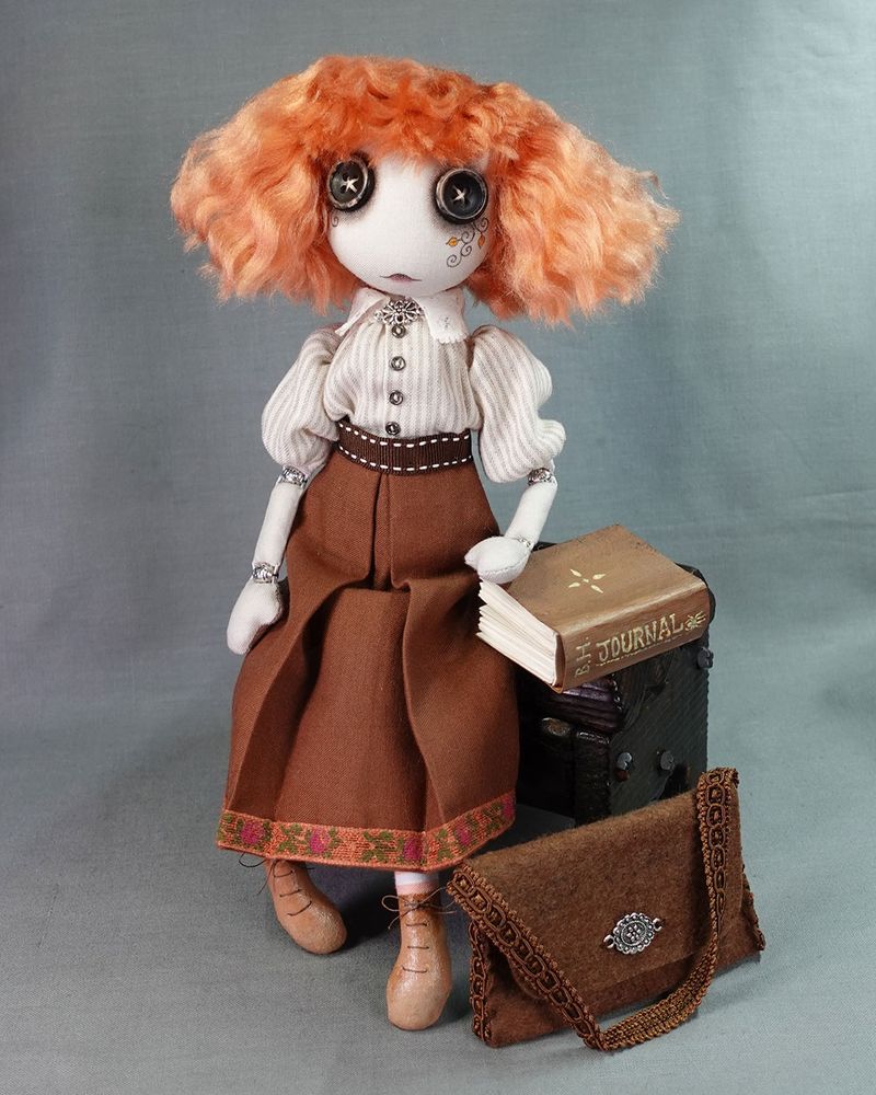 a dark academia style art doll with button eyes and red hair, in vintage style clothes with book and satchel