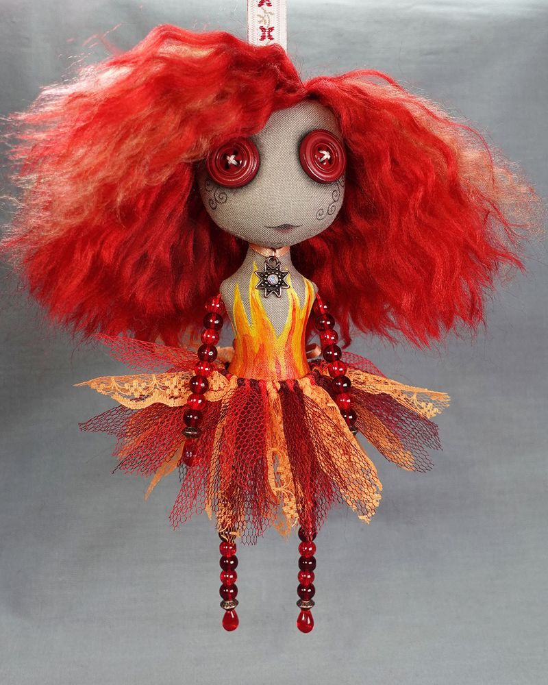 a hanging button eyed art doll in fiery reds and oranges with hand painted flames and red glass beaded limbs