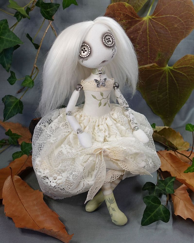 a button eyed ghost art doll with long white hair and ivory lace dress with hand painted vine detail