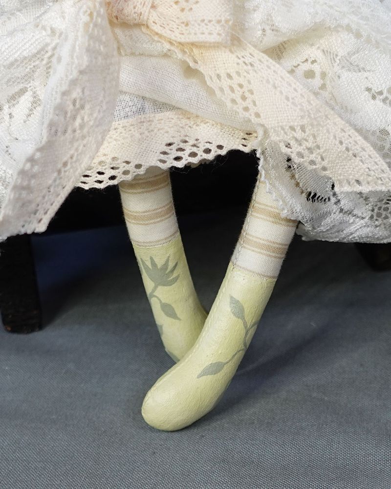 close up of hand painted doll boots with striped legs and cotton lace dress