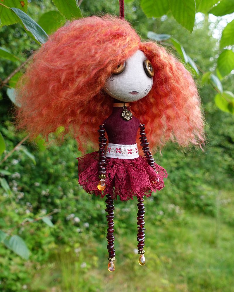 a hanging art doll in reds and golds with garnet beaded limbs