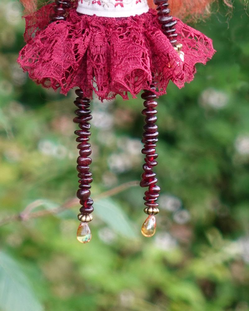 close up of beaded doll legs made from garnet chips