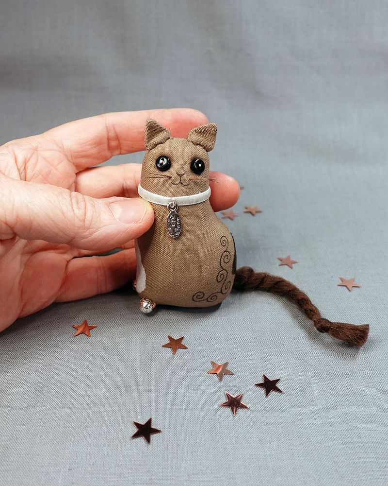 a miniature brown cloth cat with button eyes