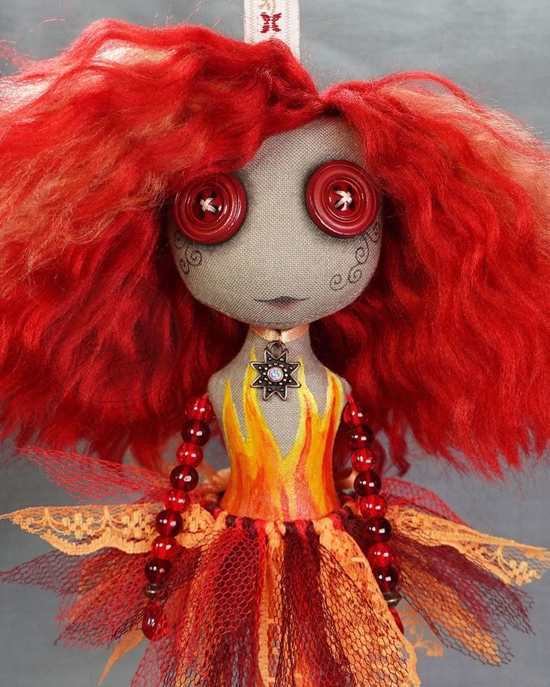 a hanging button eyed art doll in fiery reds and oranges with hand painted flames and red glass beaded limbs
