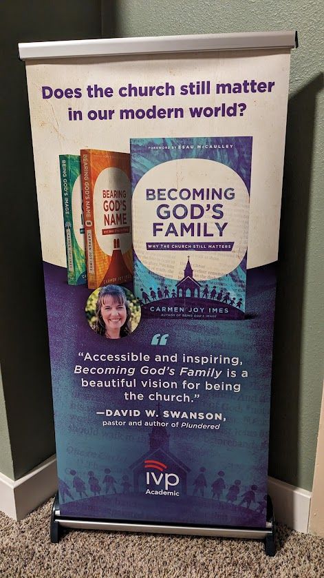 Table top banner that reads: "Does the church still matter in our modern world?" Carmen's three books are showing: Bearing God's Name, Being God's Image, and the new book, "Becoming God's Family: Why the Church Still Matters." An endorsement from pastor David Swanson is featured: "Accessible and Inspiring, Becoming God's Family is a beautiful vision for being the church."