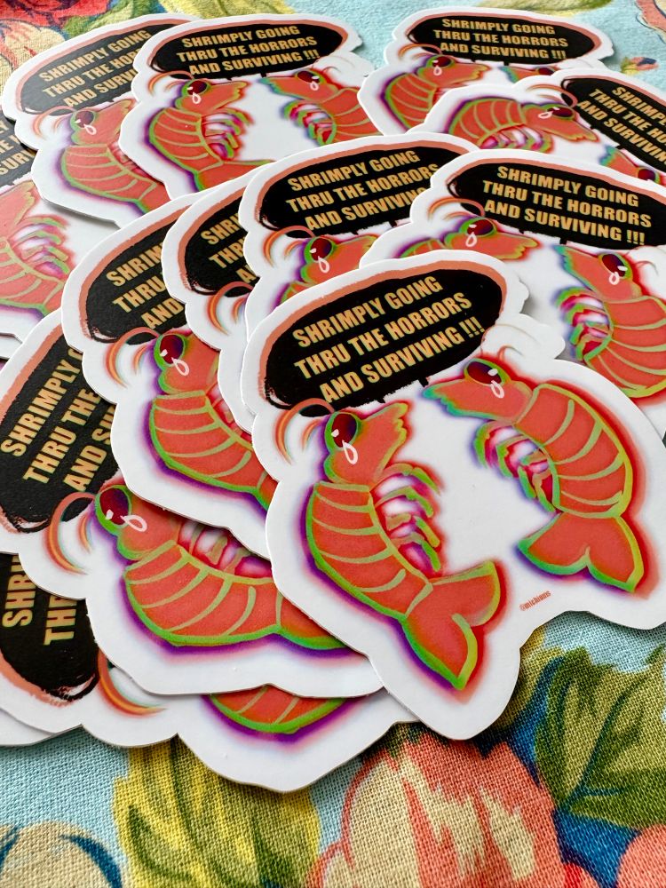 Pile of stickers with two crying shrimp that say “shrimply going thru the horrors and surviving!!!”