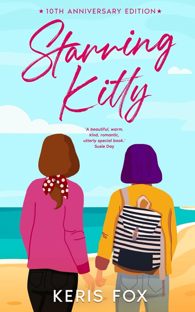 Image shows the cover of STARRING KITTY by Keris Fox. The cover has a cartoon-style of two girls seen from the back, one in a pink top and black trousers with her her reddish-brown hair tied back in a ponytail with a spotty red scarf, and one wearing a yellow jacket and grey jeans – she has bobbed purple hair and a white rucksack with vertical black stripes across it and a black pocket/flap on the front. The girls are standing on a golden beach, looking out towards the sea, which is various shades of turquoise. The sky is blue with a few white clouds in it. There is also a quote that says "A beautiful, warm, kind, romantic, utterly special book – Susie Day" 