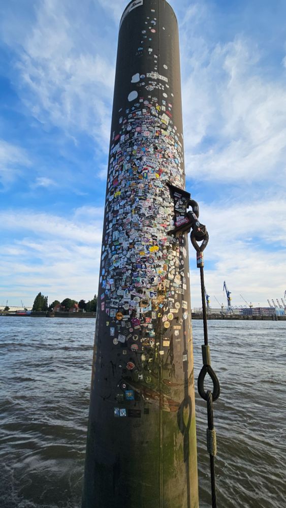Duckdalben an den Landungsbrücken bei Niedrigwasser, die bunten Flecken sind Aufkleber von allen möglichen Gruppen.
