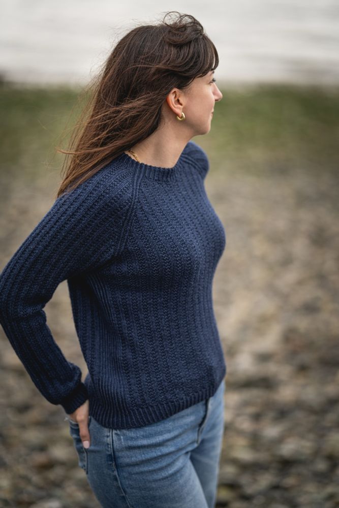 Woman wearing a top down raglan broken rib hand knit sweater on the beach