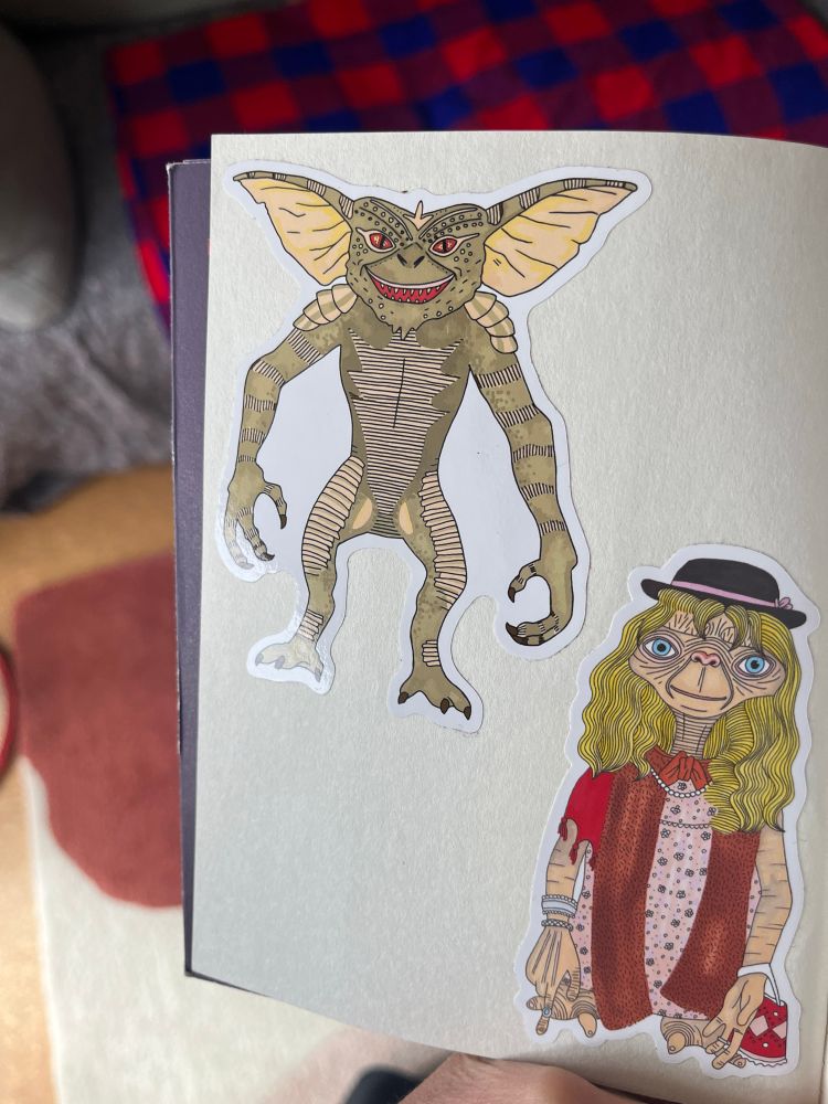 On one of the white inside pages of the book there is a large sticker of a gremlin and a large sticker of ET dressed in women’s clothing