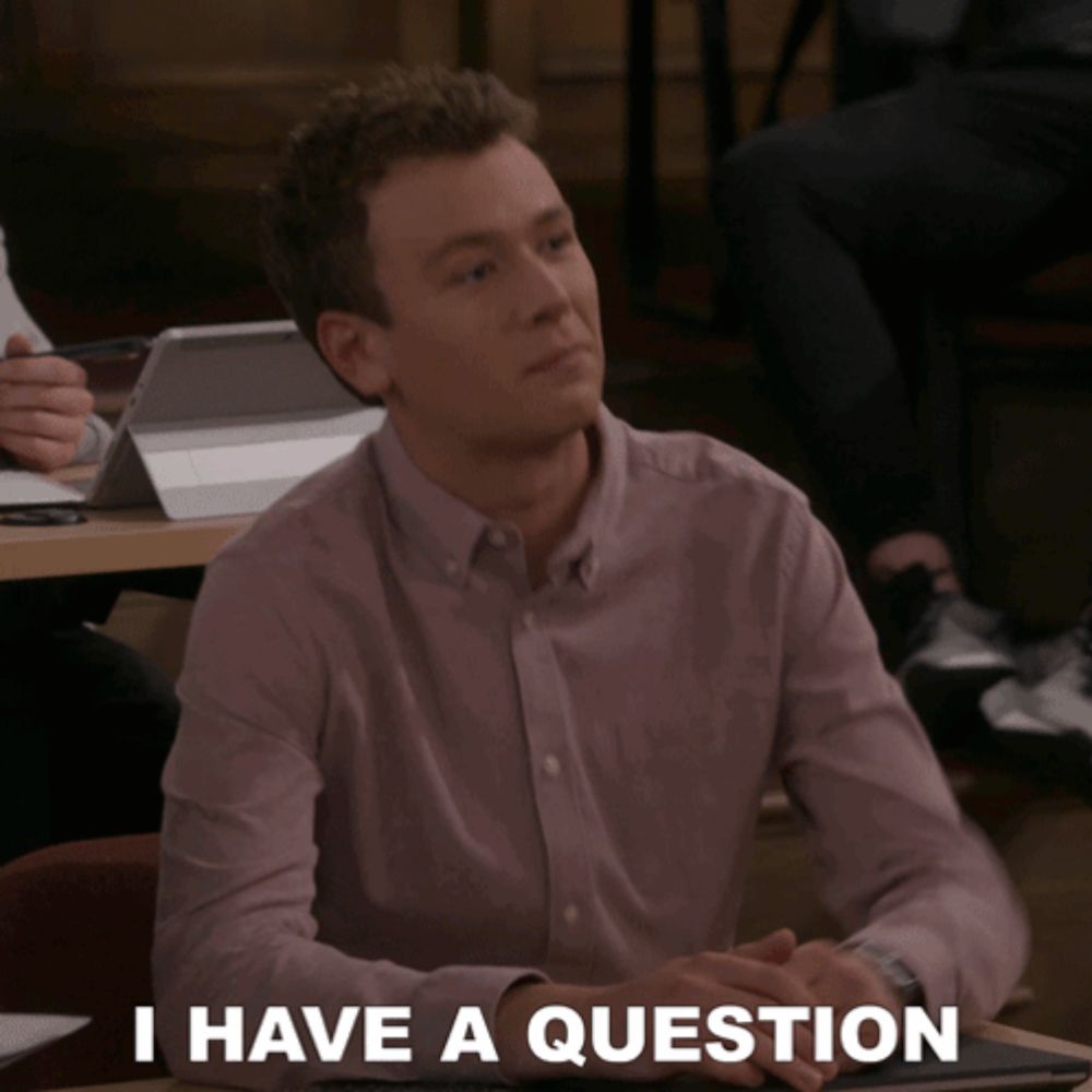 a man sitting at a table with the words " i have a question " on the bottom