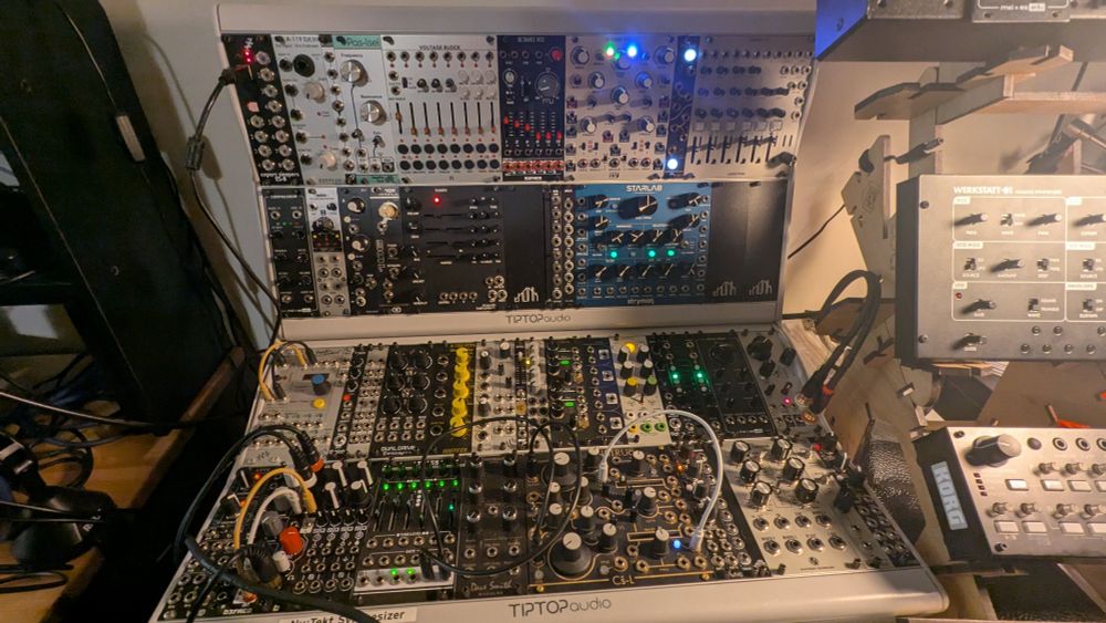 Two Tiptop Mantis 6U 104HP cases full of modules. The layout is baffling, with the master clock on the left as is tradition, but external audio input/output also mostly on the left, except for the conspicuous six-channel mixer in the top right, as far away from any output as it can get. There is no rhyme or reason to the positioning of the rest of the modules, with oscillators, filters, effects, envelopes, VCAs, and other utilities sprinkled around seemingly at random.

Spoiler: the main driver of this layout was purchase order.