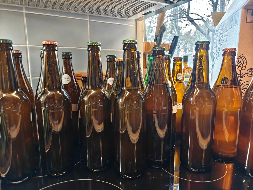 Ruskeita puolen litran lasipulloja täynnä siideriä.