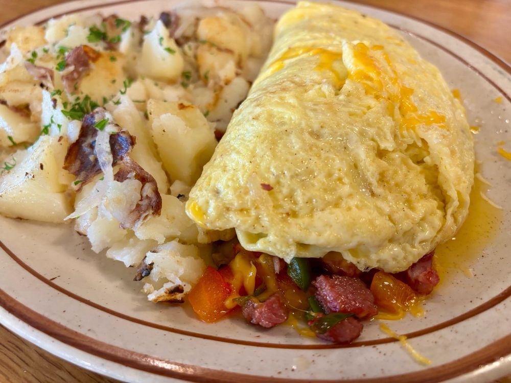 Paul’s Denver Omelet topped with melted cheese and served with a side of house potatoes. 