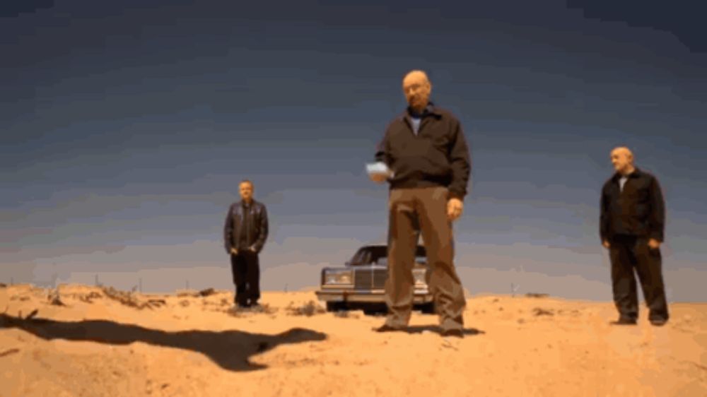 a man in a black jacket is standing in the desert with two other men