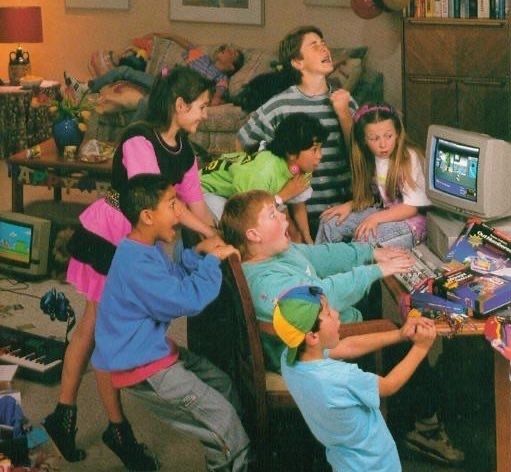 A bunch of 90s kids gathered around a desktop computer, stoked by what's happening on screen
