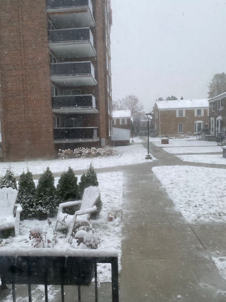 A snowy common area between townhouses and a large apartment building 