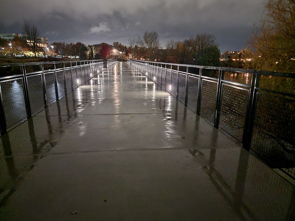 The Gonzaga footbridge at night, its lights reflected in puddles