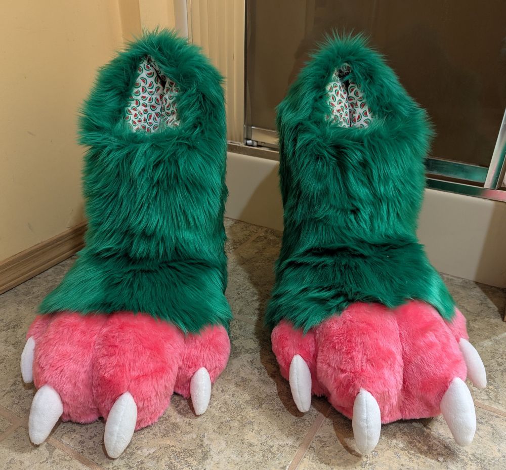 A set of green and pink digitigrade outdoor fursuit feet paws. A front view.