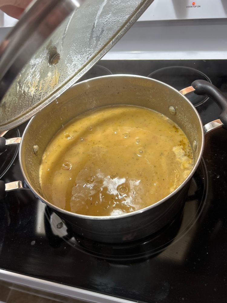 A large metal pot filled with a herb and potato soup 